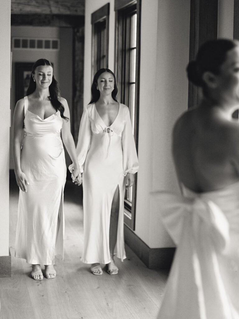 Bridesmaids holding hands for emotional first look of bride in gown at Saint Mary’s College – film photograph by Cynthia Mae Photo.
