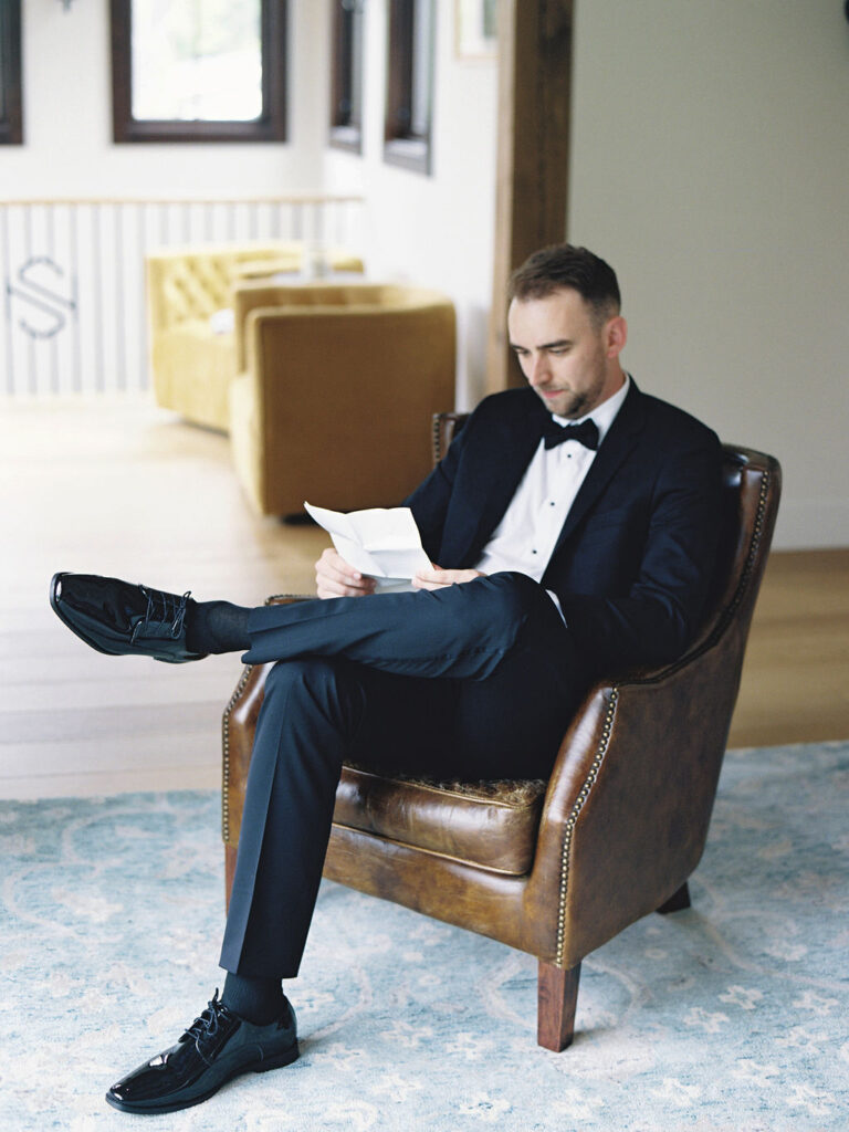 Film photo of a groom reading a hand written letter from the bride