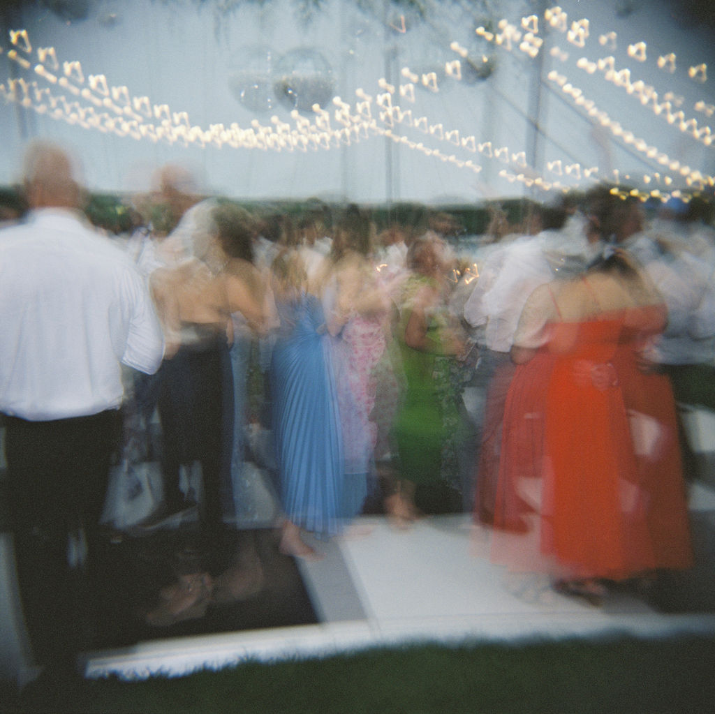 Motion blue film photo of guests on a checkered dance floor