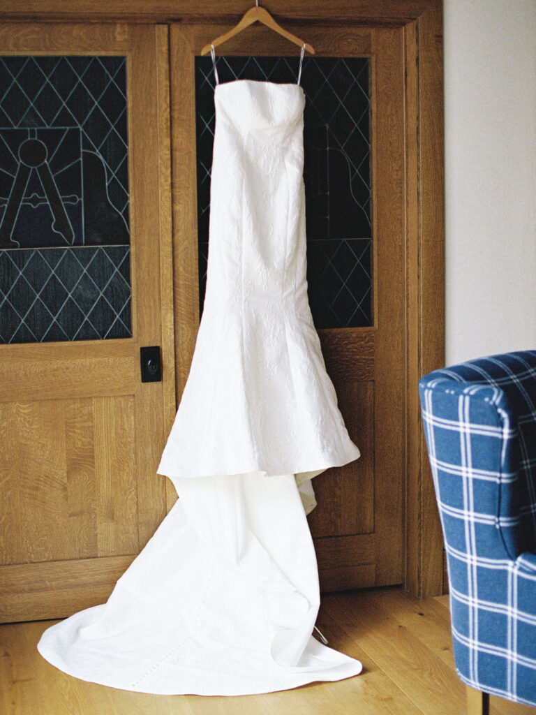 Strapless bridal gown with statement bow hanging on wooden door during Saint Mary’s College wedding preparations – Cynthia Mae Photo.