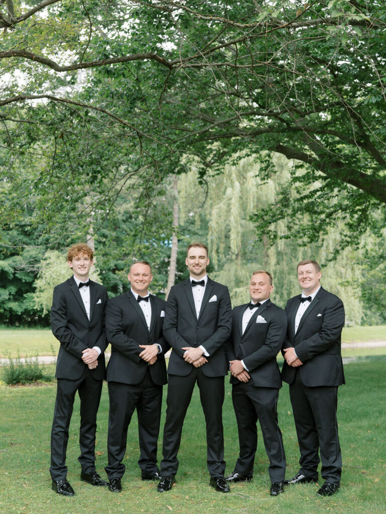Groom and groomsmen standing together in classic black tuxedos at Saint Mary’s College – Cynthia Mae Photo.