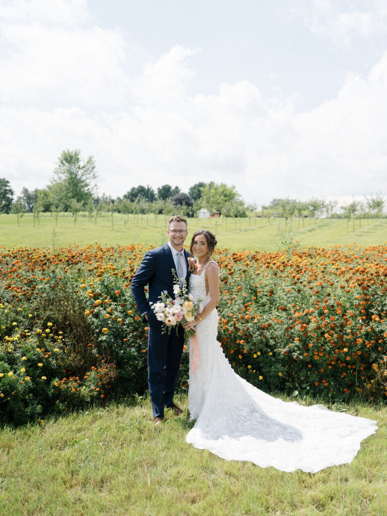 Couple standing together in colorful garden landscape at Of The Land wedding venue