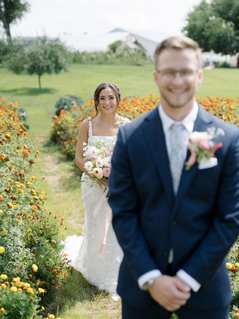 Groom standing in garden awaiting first look during an Of The Land wedding.