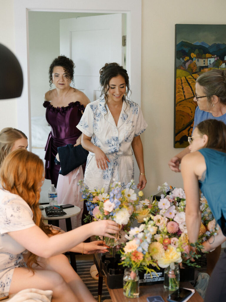 Bridesmaids putting together bouquets in the Farm Flat at Of The Land wedding venue.