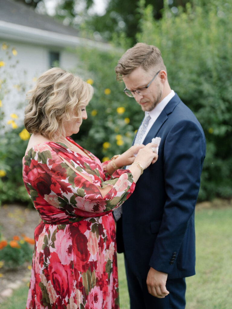 Grooms mother putting on his boutonniere. 