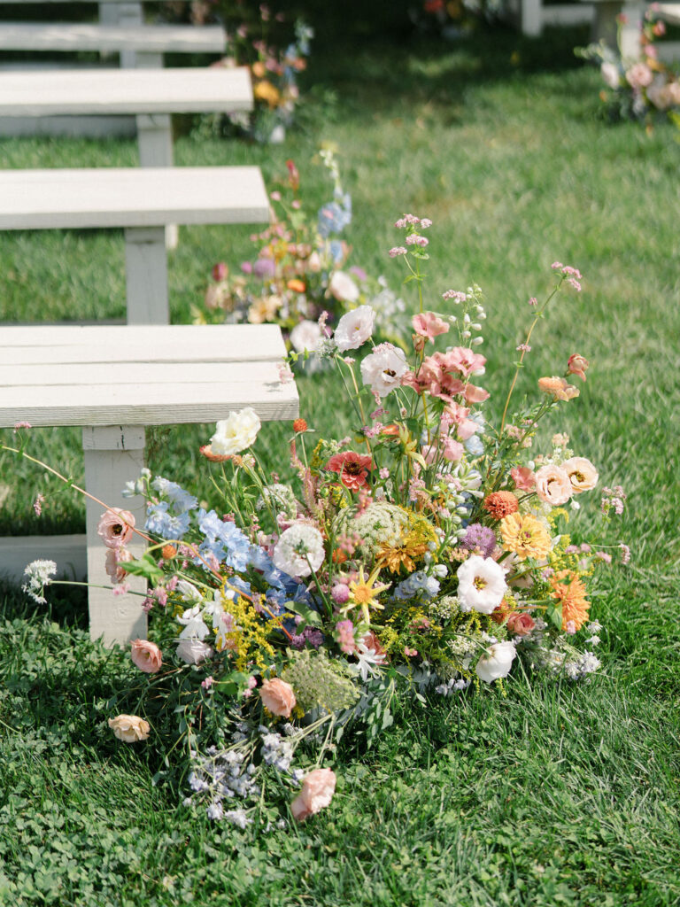 Garden-style floral arrangement lining the aisle for an Of The Land wedding ceremony.