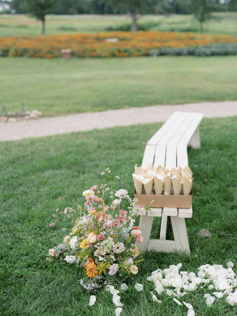 Petal cones and loose petals arranged beside ceremony benches at Of The Land wedding.