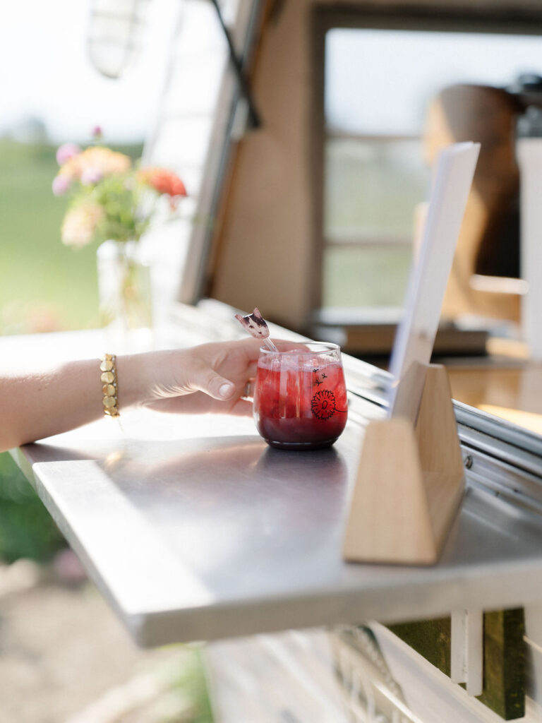 Guest receiving a signature cocktail from the vintage bar trailer at Of The Land wedding.