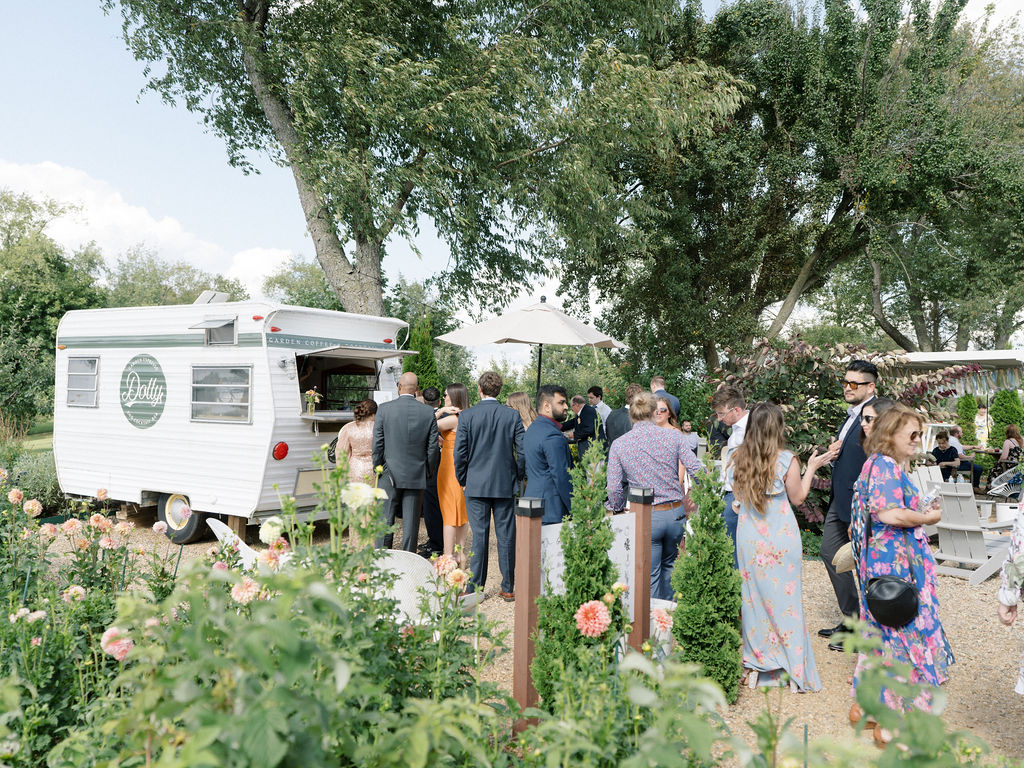 Guests gathered around the outdoor bar trailer in the edible patio garden during cocktail hour.