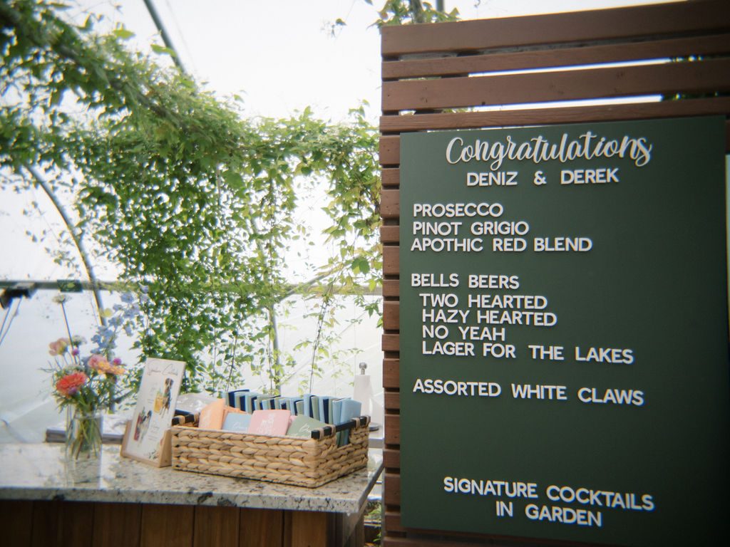 Bar menu and guest favors displayed inside the greenhouse at Of The Land wedding.
