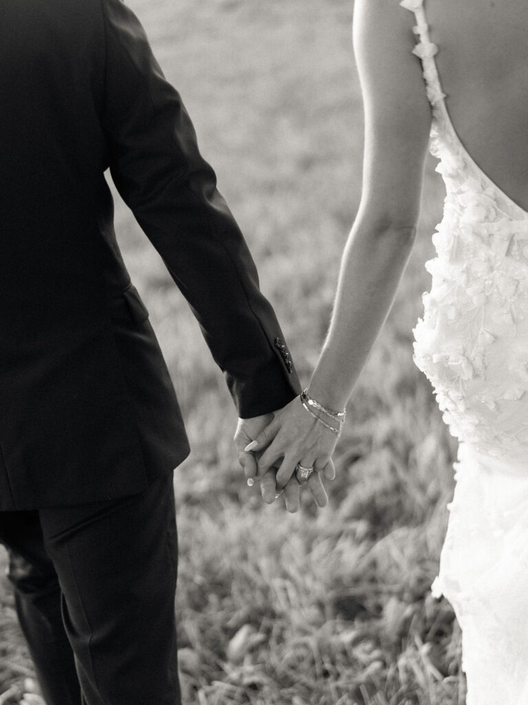 Close-up of couple holding hands while walking through the gardens at golden hour.