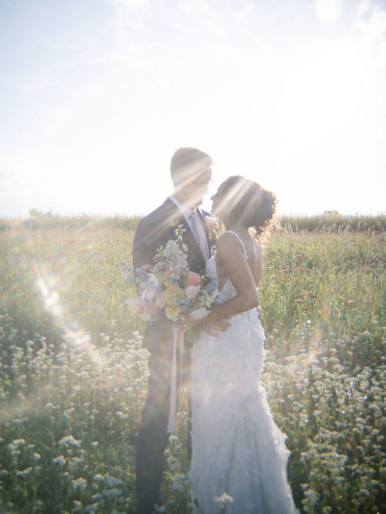 Backlit photo of couple embracing with sun rays shining through in the gardens.