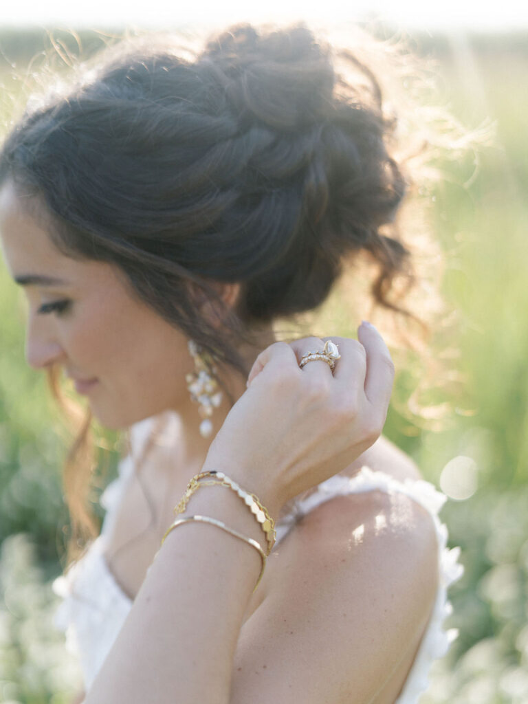 Bride adjusting her bracelets in soft golden hour light at Of The Land.