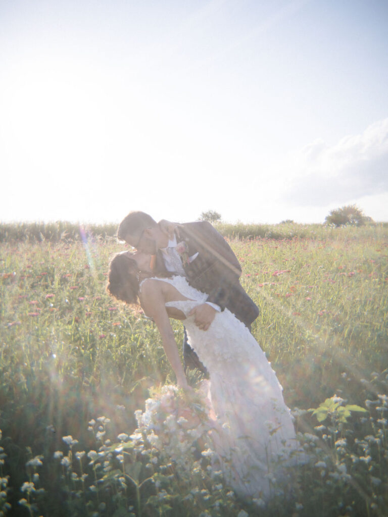 Dreamy photo of a bride and groom kissing in the gardens at Of The Land wedding venue in Michigan.