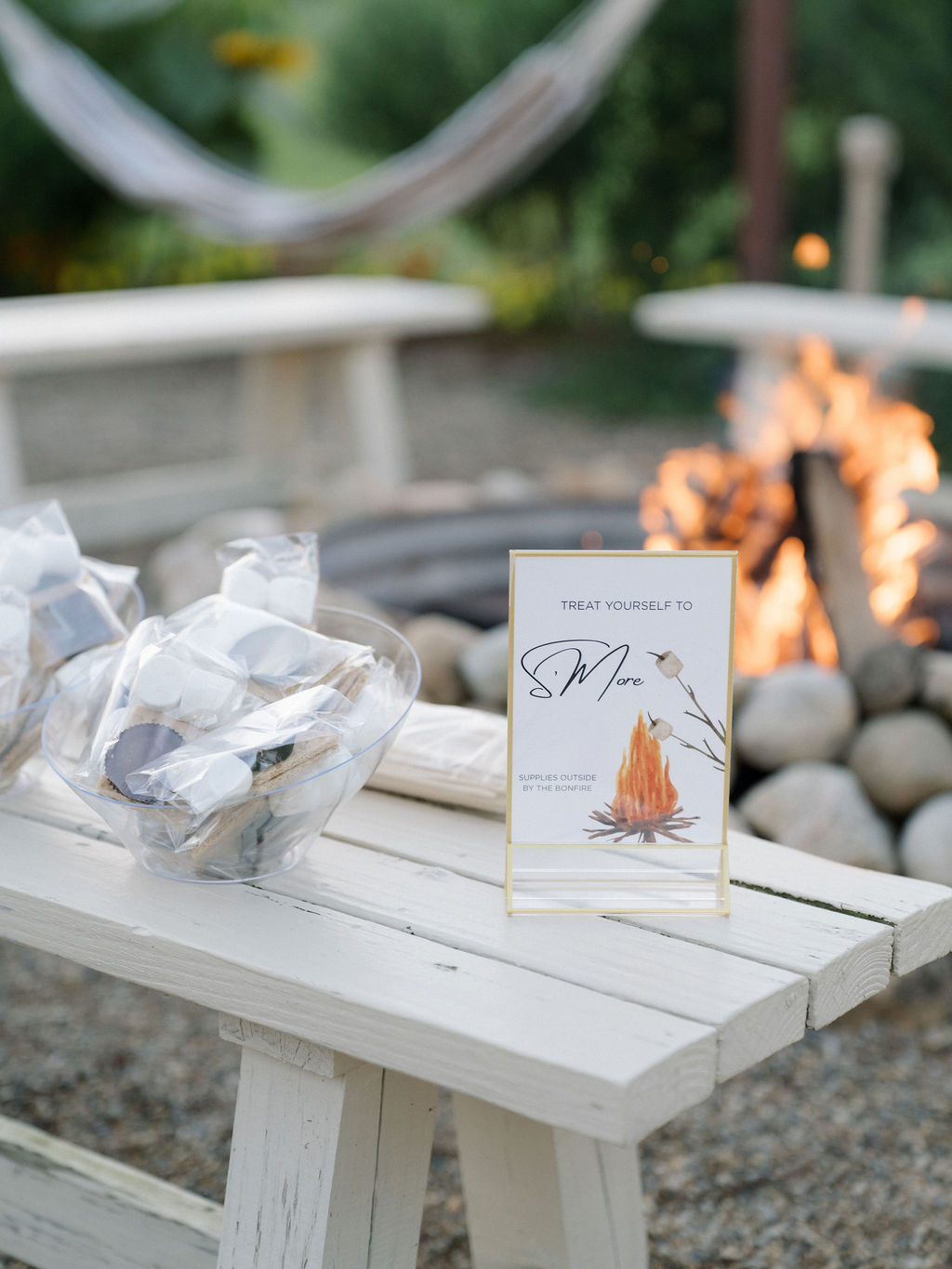 Outdoor s’mores station set beside a bonfire at an Of The Land wedding, with pre-packed ingredients and a cozy firepit.