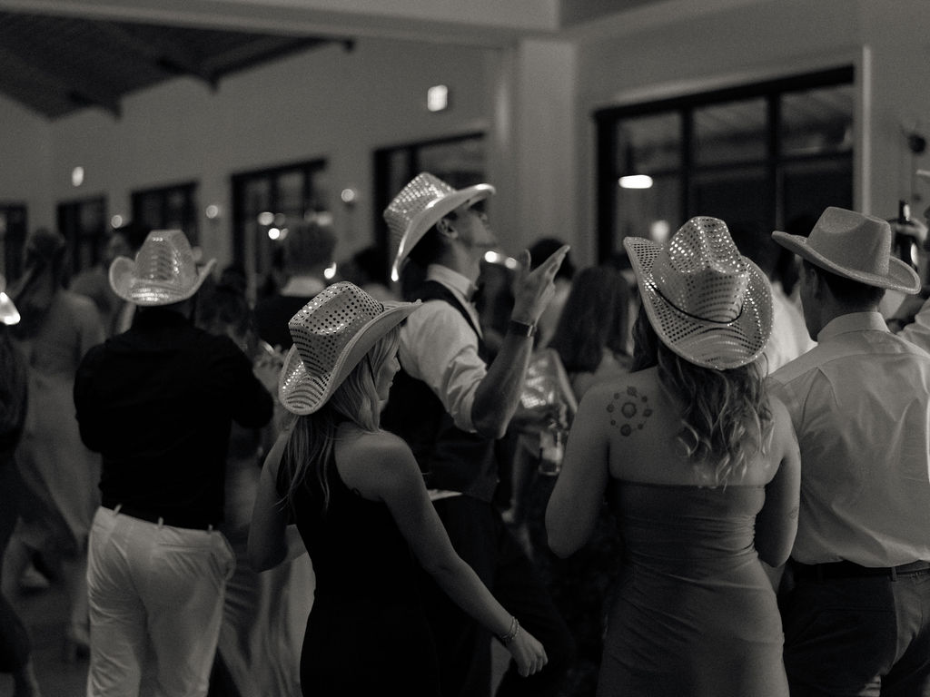 Black and white photo of guests with cowboy hats dancing.