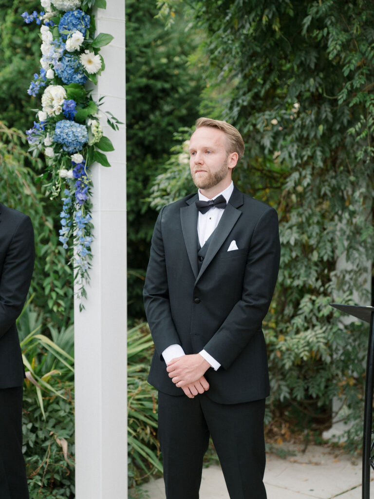 Groom waiting and watching his bride walk down the aisle.