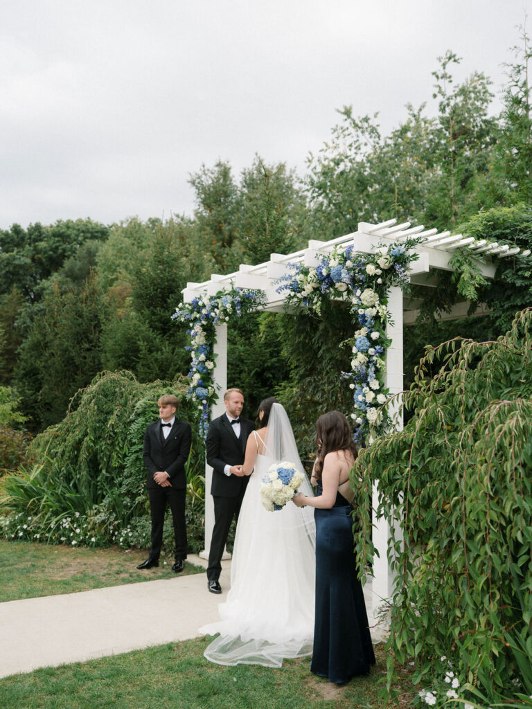 Bride and groom holding hands at the altar during their Bay Pointe Woods wedding ceremony.