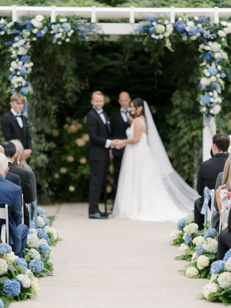 Bride and groom holding hands at the altar during their Bay Pointe Woods wedding ceremony.