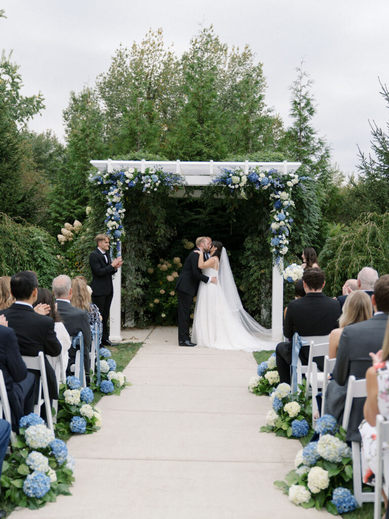 Bride and groom kissing during their Bay Pointe Woods wedding ceremony.