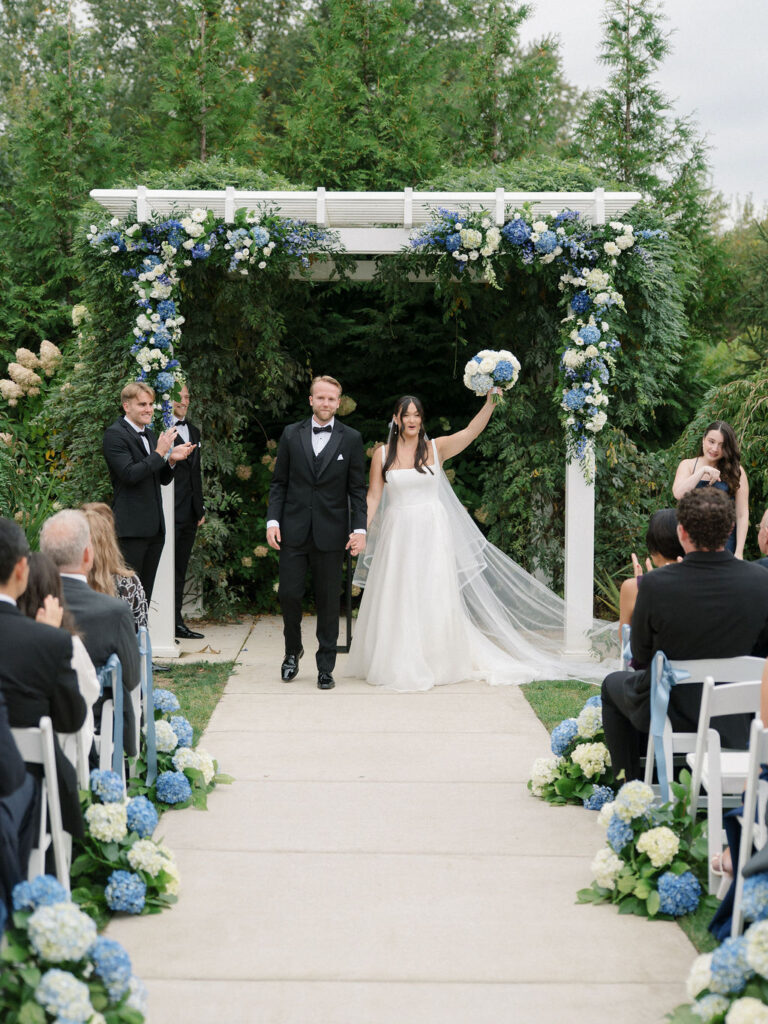 Bride and groom walking back down the aisle as husband and wife after their Bay Pointe Woods wedding ceremony.