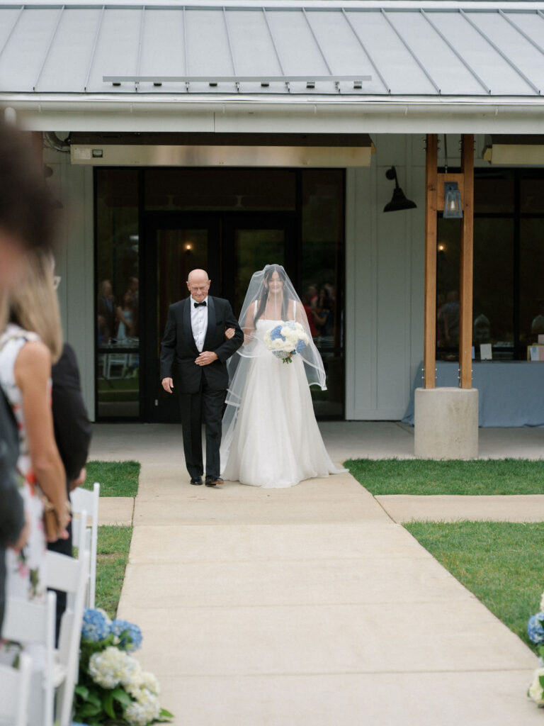 Bride walking down the aisle with her father for her outdoor Bay Pointe Woods wedding ceremony.