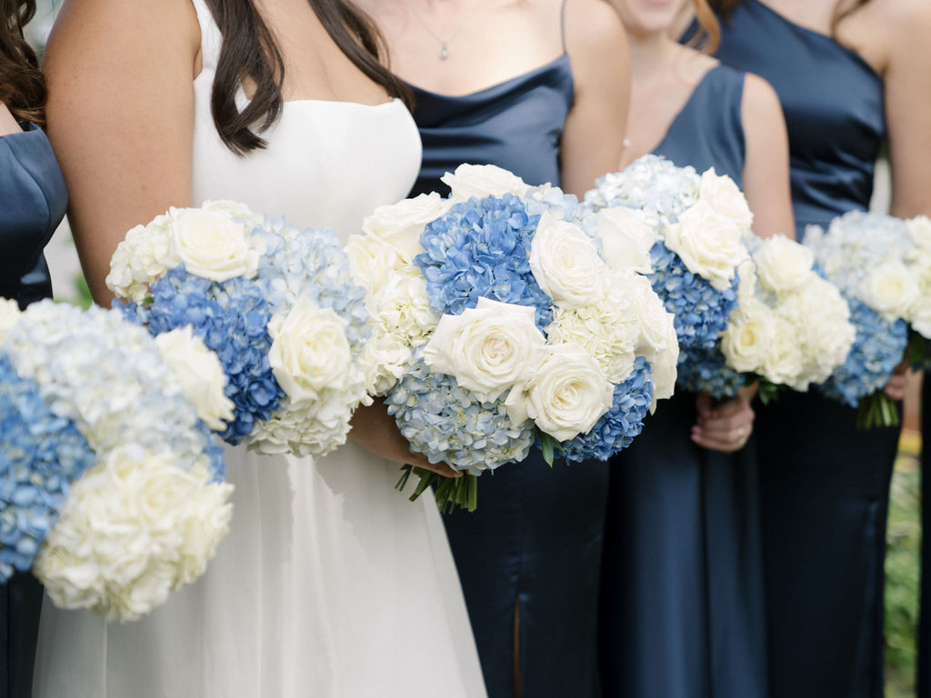 Close-up of blue and white wedding bouquets held by the bride and bridesmaids at Bay Pointe Woods.