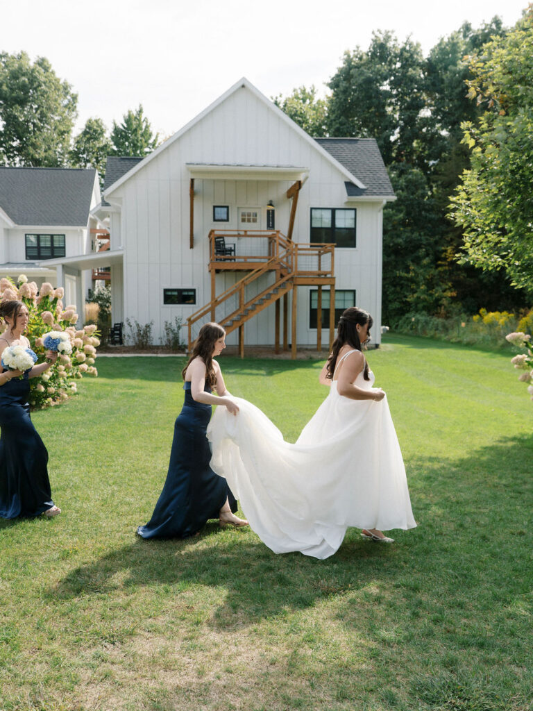 Bride walking with her bridesmaids across the lawn at Bay Pointe Woods before the ceremony.