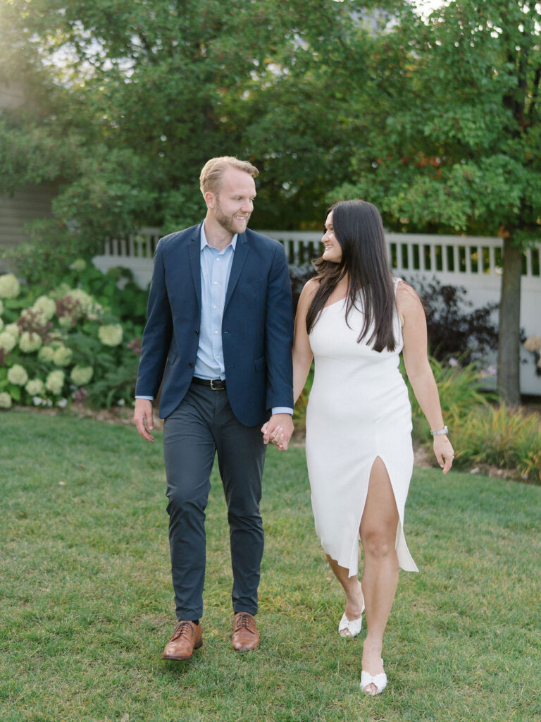 Bride and groom walking hand in hand on the lawn during their wedding weekend.
