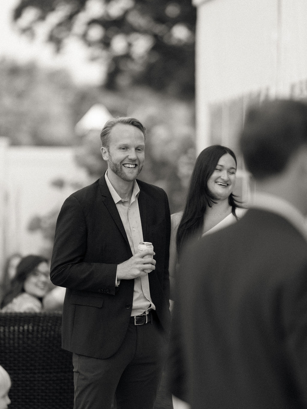 Groom and bride smiling with guests during a Bay Pointe Woods rehearsal gathering.