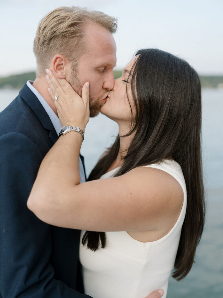 Bride and groom sharing a kiss by the lake during their Bay Pointe Woods wedding weekend.