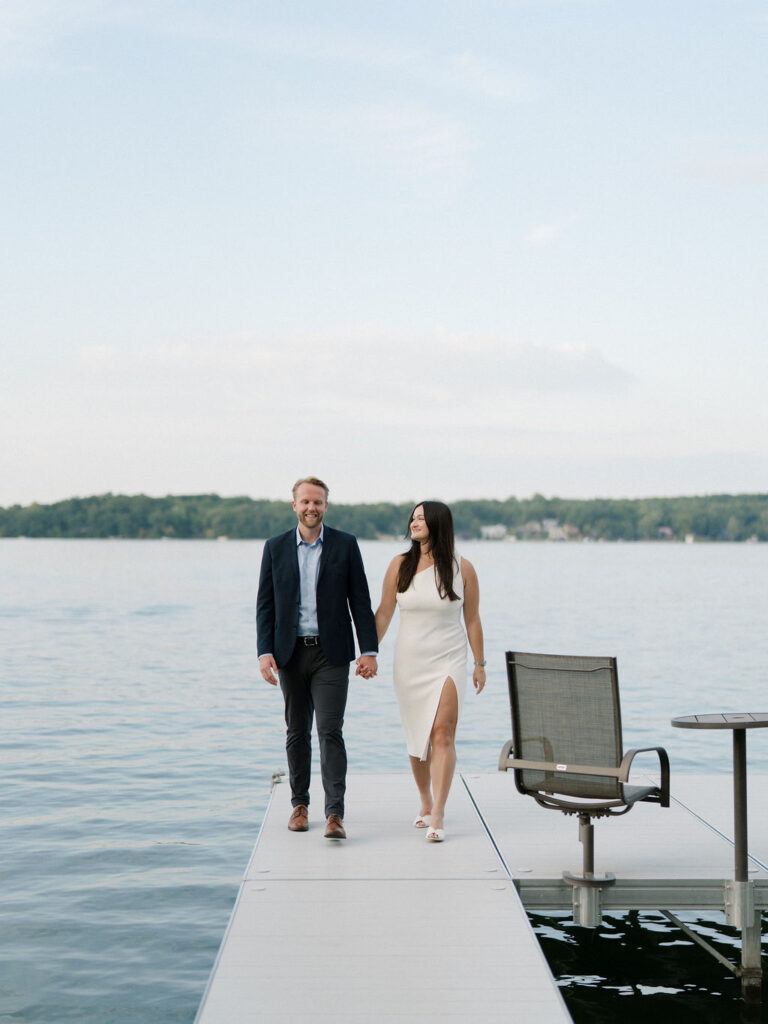 Bride and groom walking hand in hand along the dock at Bay Pointe Woods.