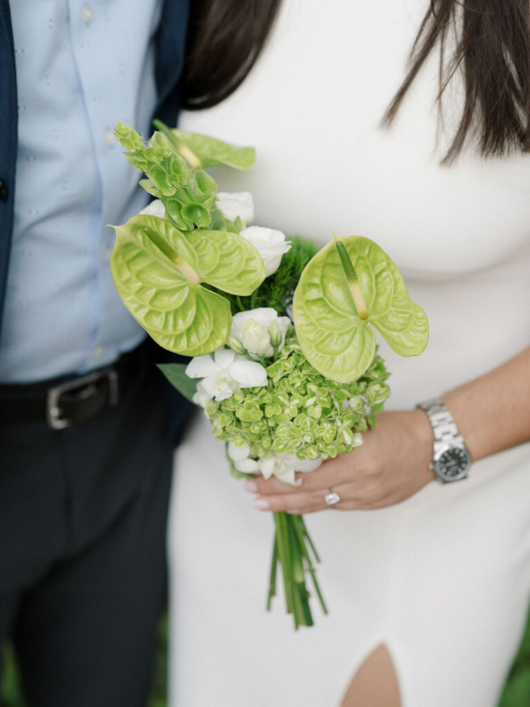 Close-up of the bride’s bouquet with green anthurium flowers during a lakeside wedding.