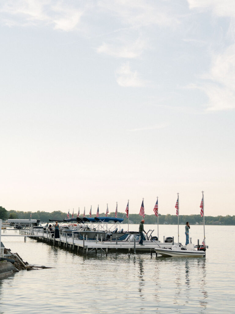 Dock lined with American flags on the lake during a Bay Pointe Woods wedding weekend.