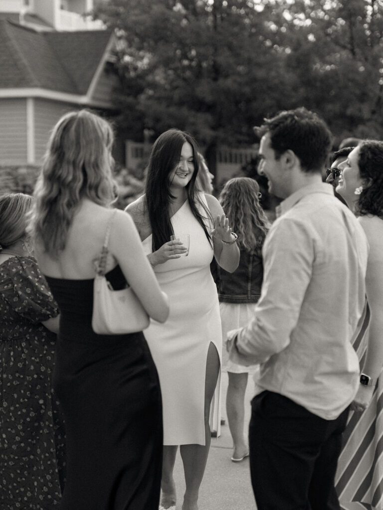 Bride chatting and laughing with guests during a relaxed wedding rehearsal celebration.