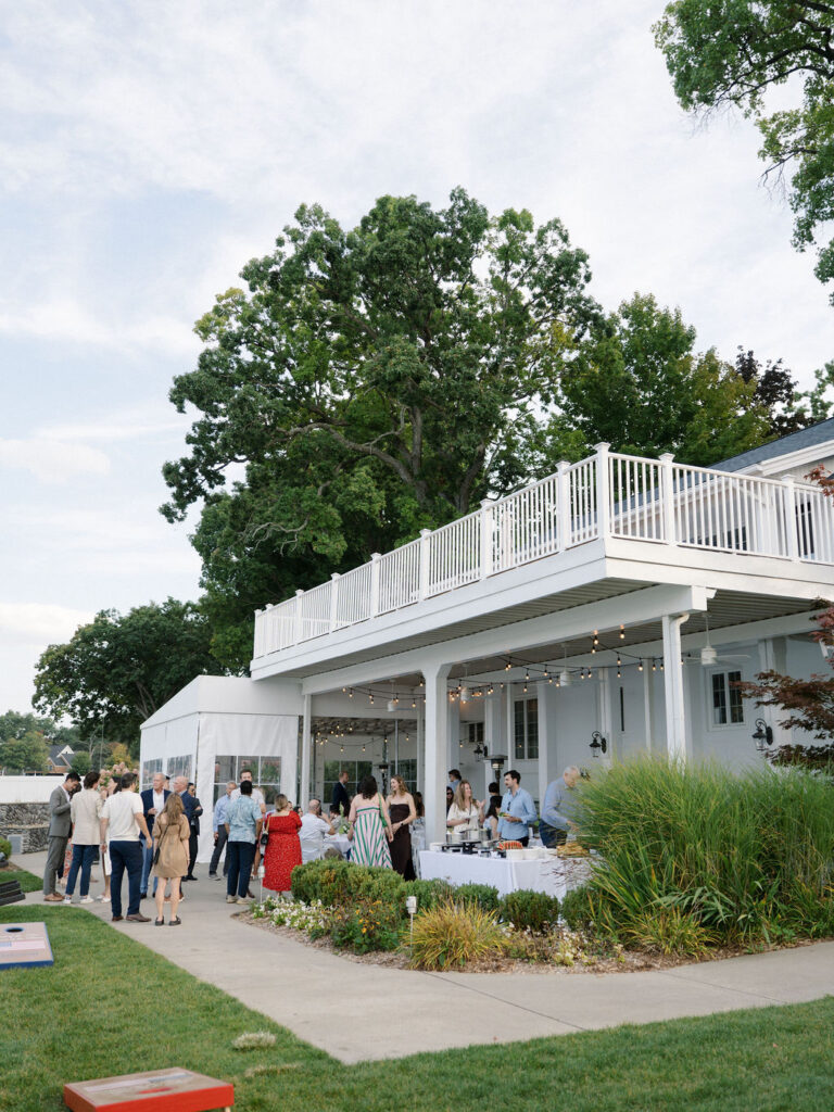 Guests mingling under the Lakefront Pavilion during a Bay Pointe Woods wedding rehearsal.