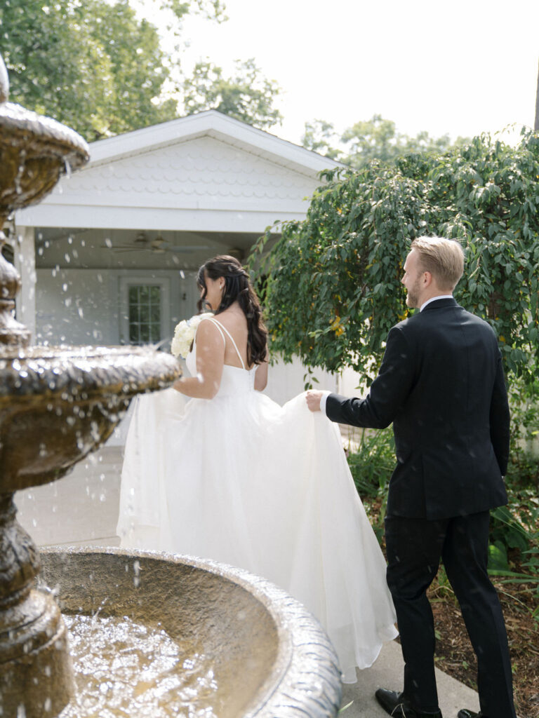 Bride and groom walking around the water fountain at Bay Pointe Woods.