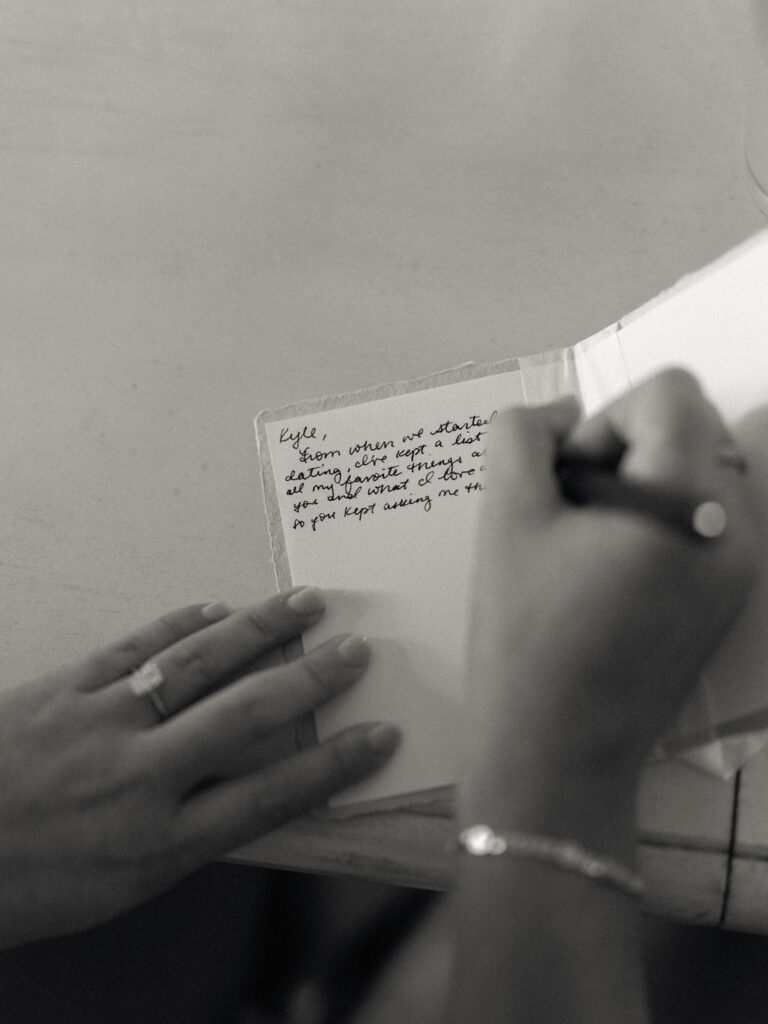Black and white photo of a bride writing her vows to the groom.