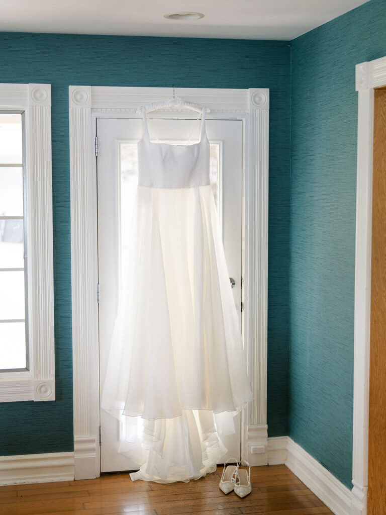 Brides wedding dress hanging off a door frame.