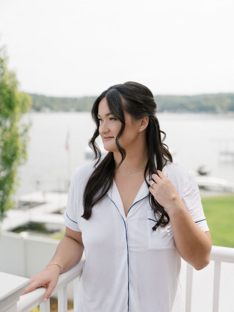 Bride in white pajamas looking out over Gun Lake while getting ready at Bay Pointe Inn.