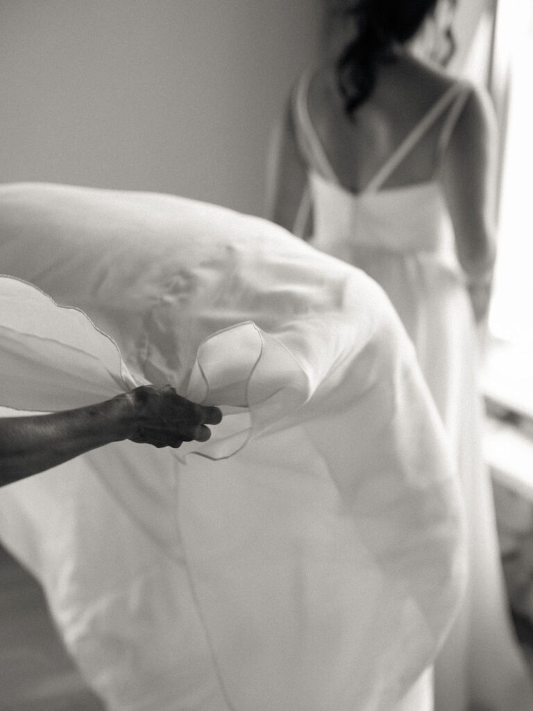 Candid photo of the mother of the bride fluffing her wedding dress.