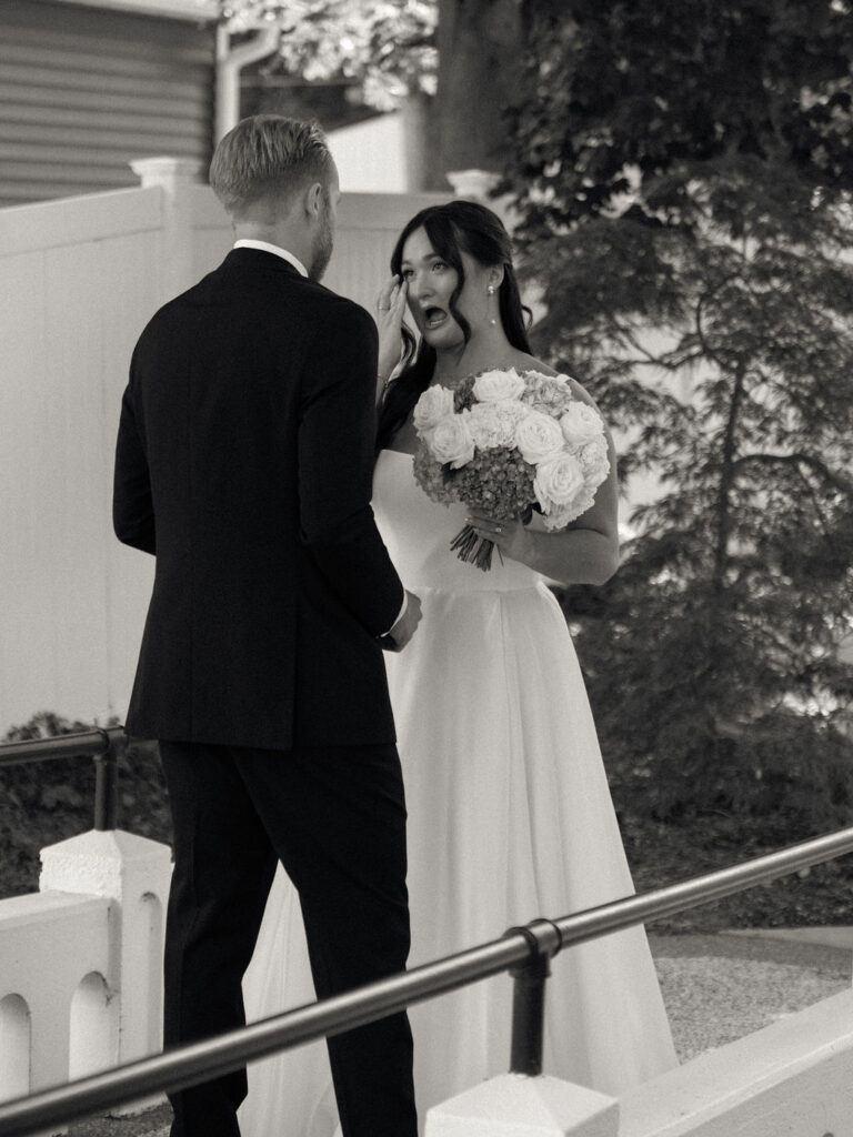 Emotional first look between the bride and groom with Gun Lake in the background.