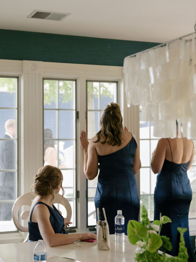 Candid wedding photo of bridesmaids watching the bride and groom after their first look.