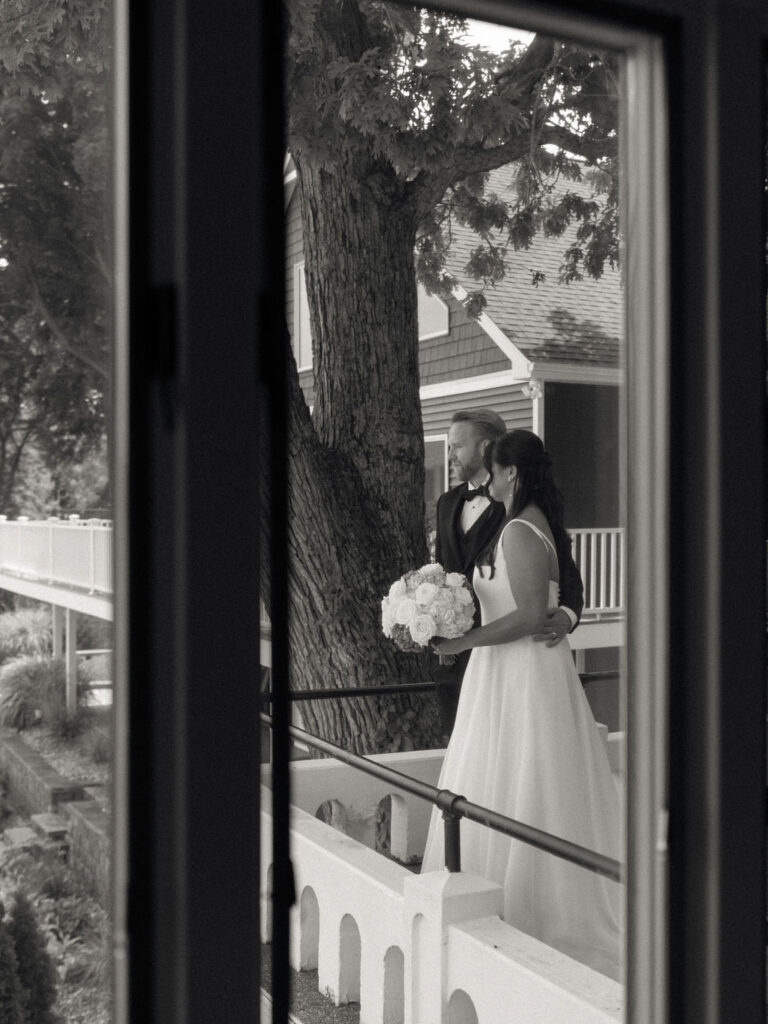 Black and white documentary style photo of a bride and groom admiring Gun Lake during their first looks at Bay Pointe Woods.